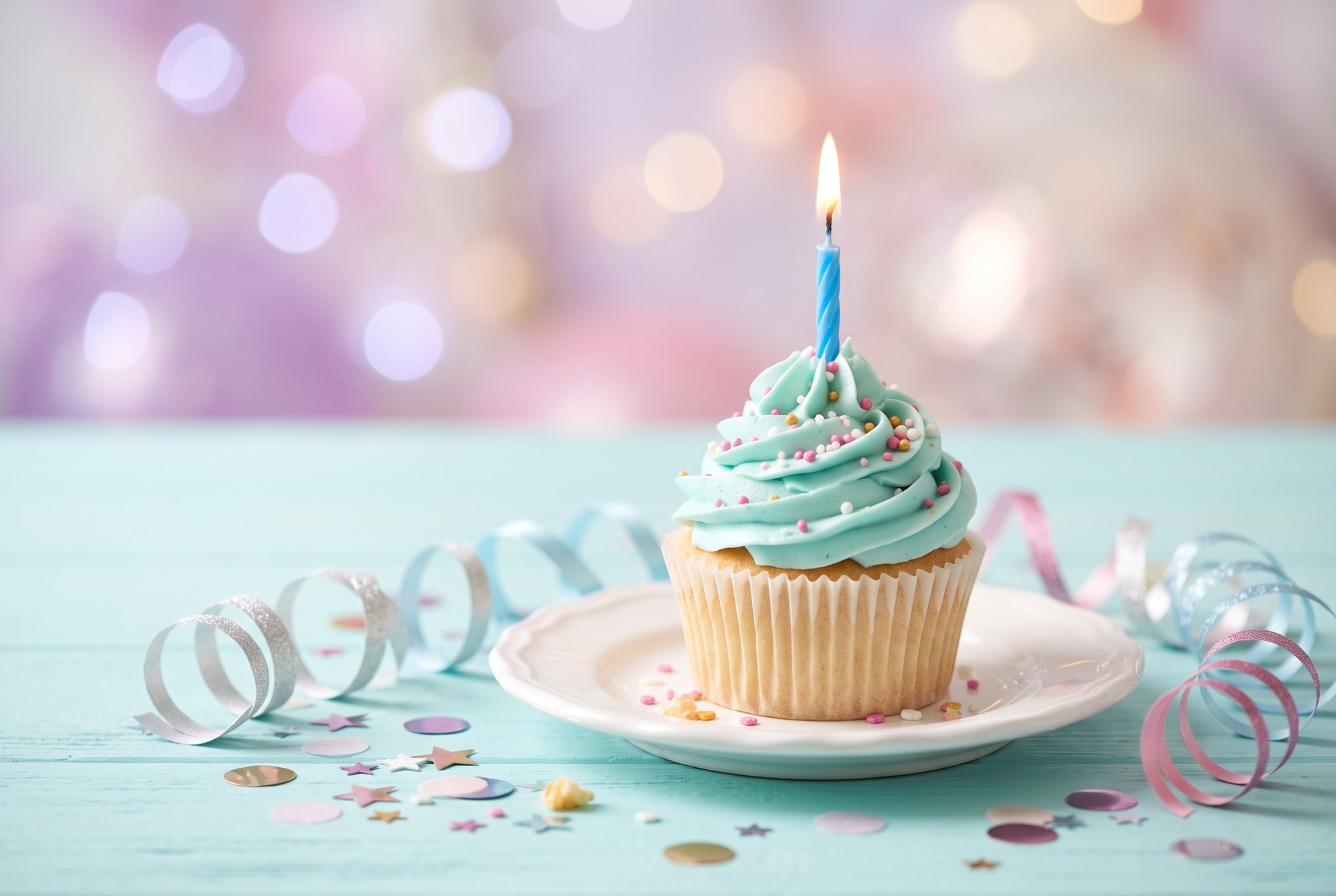 Cupcake mit Kerze vor bunten Lichtern